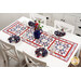 The completed table runner in red, white, and blue floral fabrics from the Forever Blooms collection, displayed on a white table surrounded by matching napkins on white plates, water glasses, and a coordinating bouquet. There is a gold Shabby Fabrics in the bottom right corner.