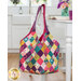 The completed Mondo bag in the bright pink, turquoise, and citron floral fabrics from the Parlor collection, hanging over the back of a white wooden chair with coordinating décor on the table beside it.
