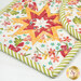 A close up on the square hot pad, demonstrating color and print details on the white vermillion, green, and orange fabrics.