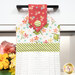 A close up shot of the top of the hanging towel. Stylized florals can be seen in the white fabric.