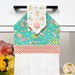 A close up shot of the top of the hanging towel. Stylized florals can be seen in the teal fabric.