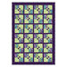 Quilt featuring a patterned design with squares in green, purple, and floral motifs arranged neatly.