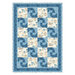 A patchwork quilt featuring alternating blue and cream squares with a swirl pattern and floral designs.