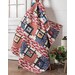 A colorful quilt draped over a rustic chair, featuring red, white, and blue patterns with stars.