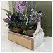 The fully assembled and painted Planter Box Cross Stitch Display, staged on a marble tabletop with two potted purple bouquets.
