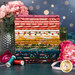 A stack of the fabrics included in the Corsage collection, with flowers and a vase and jars and ribbon and thread.