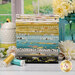 A stack of the fabrics included in the Pollinators collection, with a window and flowers and a beehive and a jar and thread.