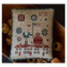 The completed cross stitch finished as a pillow sitting in a wooden bowl surrounded by coordinating décor.