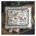 The completed cross stitch finished as a pillow sitting in a wooden bowl surrounded by coordinating décor.