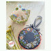 Front of pattern showing the completed cross stitch projects finished as a pincushion and a wreath.