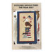 The front of the Stitched Spools Thru The Year July pattern, featuring the completed cross stitch design of an eagle on stop of a patriotic spool holding an American flag, stitched on a small mat surrounded by coordinating décor.