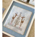 The completed Winter Reindeer cross stitch project, staged on a textured table.