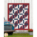 The completed Steadfast Quilt finished in patriotic themed fabrics from the American Gatherings III collection by Moda fabrics, hung on a rustic paneled wall with a blue truck out front. 