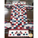 The completed American Glory Table Runner finished in patriotic fabric from the American Gatherings III collection by Moda, on a wooden tabel with four table settings. 