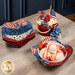 The completed bowl cozies, three stacked and one holding a bowl of ice cream with strawberries and syrup, staged with decorative plates and a floral arrangement.