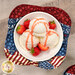 A top down shot of the bowl cozy, holding a white bowl of vanilla ice cream with strawberries.