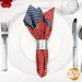 A top down shot of the napkin with the red fabric faced out, staged on a white table setting with silverware and a glass.