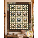 The completed Northwoods Lodge Quilt, featuring rows of patchwork stars paired with panels, colored in earthy neutral fabrics, and staged in a cozy cabin setting.
