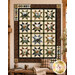 The completed Northwoods Lodge Quilt, featuring rows of patchwork stars paired with panels colored in earthy neutral fabrics, and staged in a cozy cabin setting.