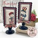 The two completed cross stitch projects of Sam and Betsy, set on parchment cream fabric and stitched with rustic colors, displayed on a Paisleys and Polka Dots mount.