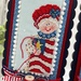 A close up on the bright version of Betsy, holding a needle with a red thread through it.