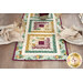 A top-down shot of the table runner on the set white table with place settings, showcasing the log cabin piecing.