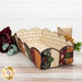 The completed Scalloped Basket, colored in primitive fabrics from the Quail Run collection by Moda, staged on a wooden table with coordinating flowers and décor.