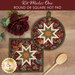 The two completed cream Folded Star Hot Pads, one round and one square, slightly overlapping each other and staged on a wooden table with coordinating floral décor.