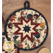 A super close up on the center of the round hot pad, demonstrating the cream fabric details on the beautiful folded star center.