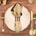 A top down shot of the napkin with the cream floral side out; the napkin is staged with a white plate, silverware, and matching cup.