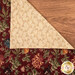 The cloth napkin laid flat on a table red floral side up with the corner folded over showing off the cream floral side.