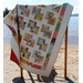 The completed Danish Delights quilt, hung on a quilt ladder and staged on a sandy beach on a sunny day.