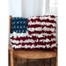 The completed decorative proddy and punch pillow on a wooden chair, colored in red, white, and blue wool and yarn.