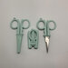 Three pairs of mint-colored scissors arranged side by side on a white surface.
