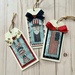 The three completed cross stitch projects, mounted on wooden tags with fabric bow accents.