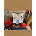 cross stitch pattern finished as a pillow featuring a 1776 pot with florals, and a flag staged with decor and bordered by cursivescript