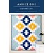 A colorful quilt titled Andes Ode featuring geometric patterns in blue, yellow, and pink on a light background.