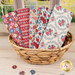 A stack of the Village Life - Burgundy fat quarter bundle, with a basket and a window and a garden and buttons.
