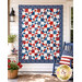 The finished Playing Favorites Quilt, colored in red, white, and blue fabrics from the Front Porch Charm collection, staged on a white porch wall with coordinating décor.
