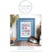 Front cover of the pattern featuring the finished piece, mounted in a blue frame and staged with matching décor.
