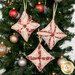 The three completed Cathedral Window Ornaments, colored in soft pink, cream, and red fabrics from the Christmas Magic collection, hung on a decorated Christmas Tree.