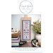 Front cover of the pattern showing the finished Hometown Summer cross stitch project mounted on a wooden cutting board, surrounded by books, thread spools, and a plant.