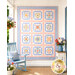 The completed Baltimore Quilt colored in soft blues, peach pinks, and cream fabrics from the Pastel Prairie collection from Moda Fabrics, staged on a white porch with coordinating décor.