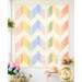 The completed Ridiculously Easy Jelly Roll Quilt colored in soft blues, peach pinks, and cream fabrics from the Pastel Prairie collection from Moda Fabrics, staged on a white porch wall with coordinating flowers and garden décor.