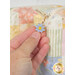 A model's hand demonstrating the blue flower zipper charm on a pastel patchwork bag.