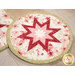 A close up on the center of the round hot pad, demonstrating the red and pink fabric details on the beautiful folded star center.