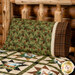 An angled shot of the pillow staged on a log wood bed and the coordinating patchwork quilt.