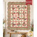 The completed Spinning Rail Fence quilt with a scalloped border in muted colors, hung on a paneled wall and staged with coordinating décor.