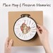 Square embroidery hoop frame with wood veneer finish with hoop placement visual.