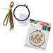 Contents of the kit, including a bundle of colorful embroidery floss next to a 6-inch hoop, Aida cloth, and a needle.